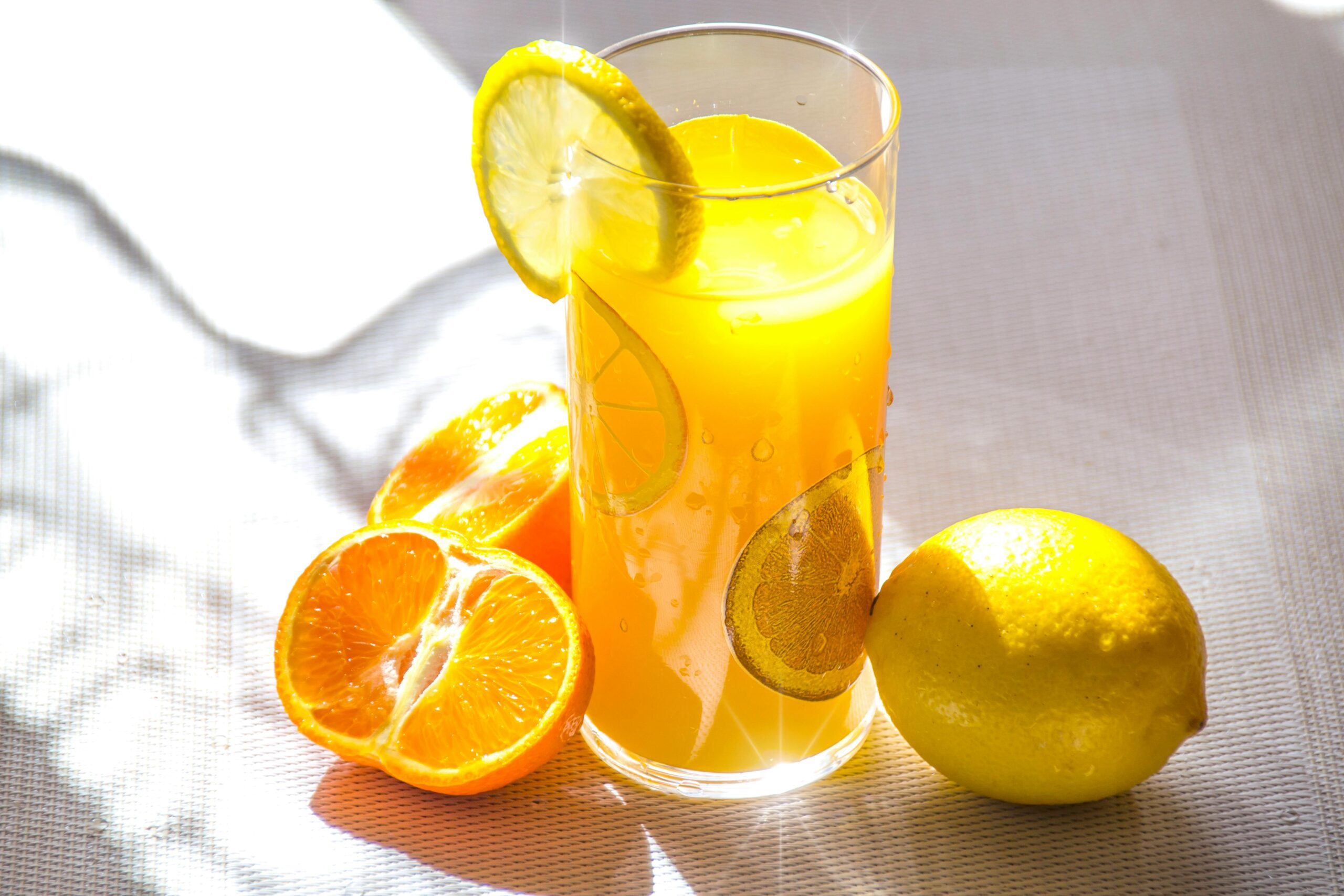 Bright and refreshing citrus juice in a glass with fresh lemon and orange slices.